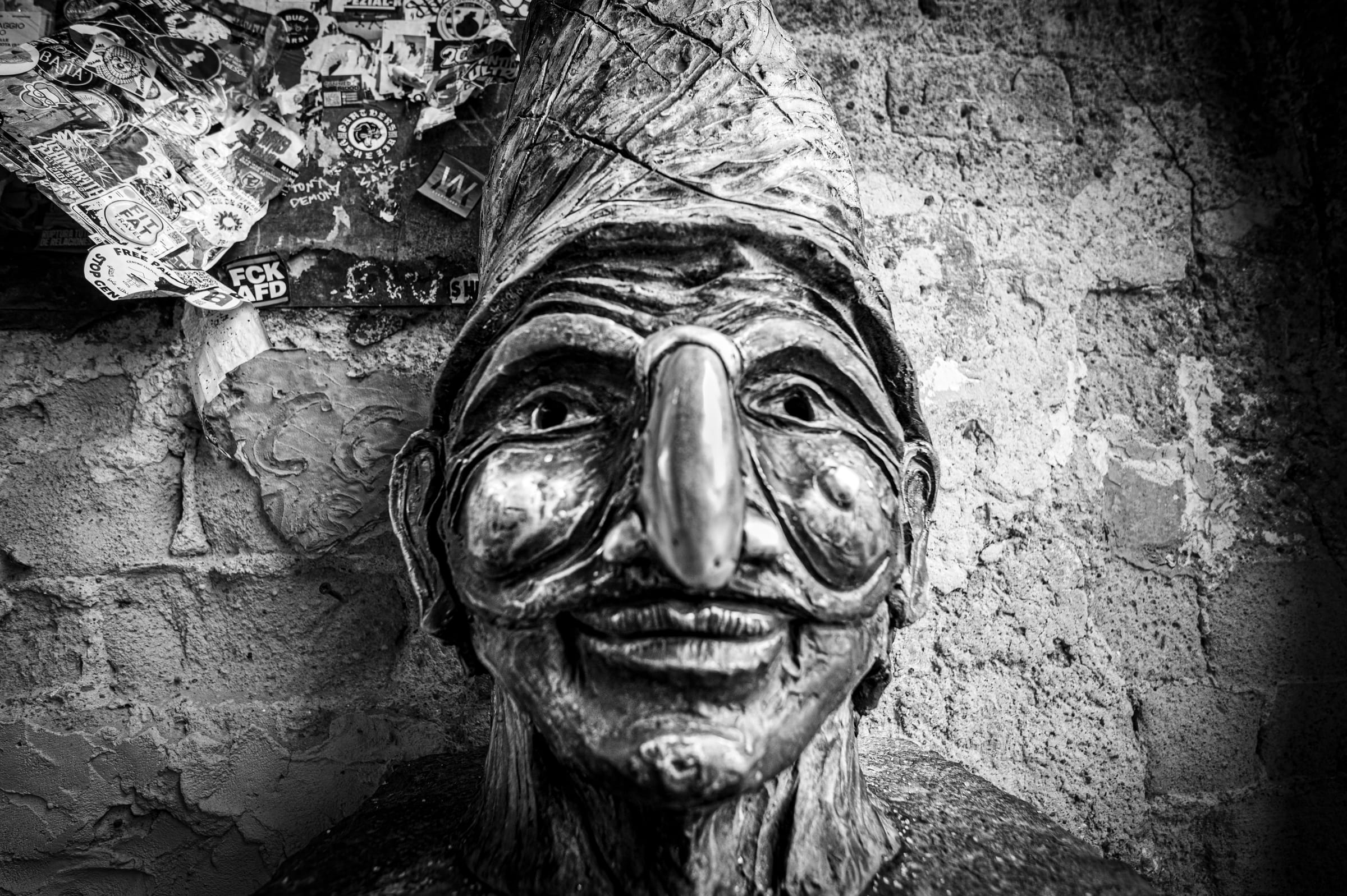 Una maschera di Pulcinella appesa a un muro scrostato del centro storico di Napoli